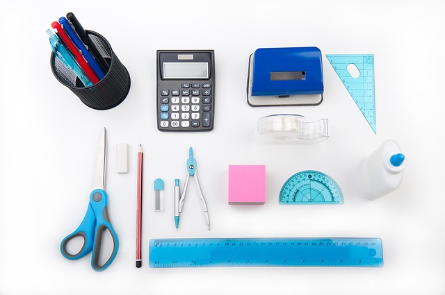 A group of office items: pens, calculator, scissors, pencil, ruler, stick notes, glue, tape and measuring tools